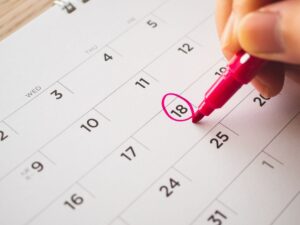 オフィスのカレンダーを見ながら派遣契約の期間を確認している人事担当者