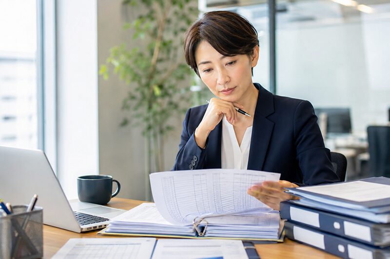 派遣先管理台帳の書類を確認するビジネスパーソンの手元